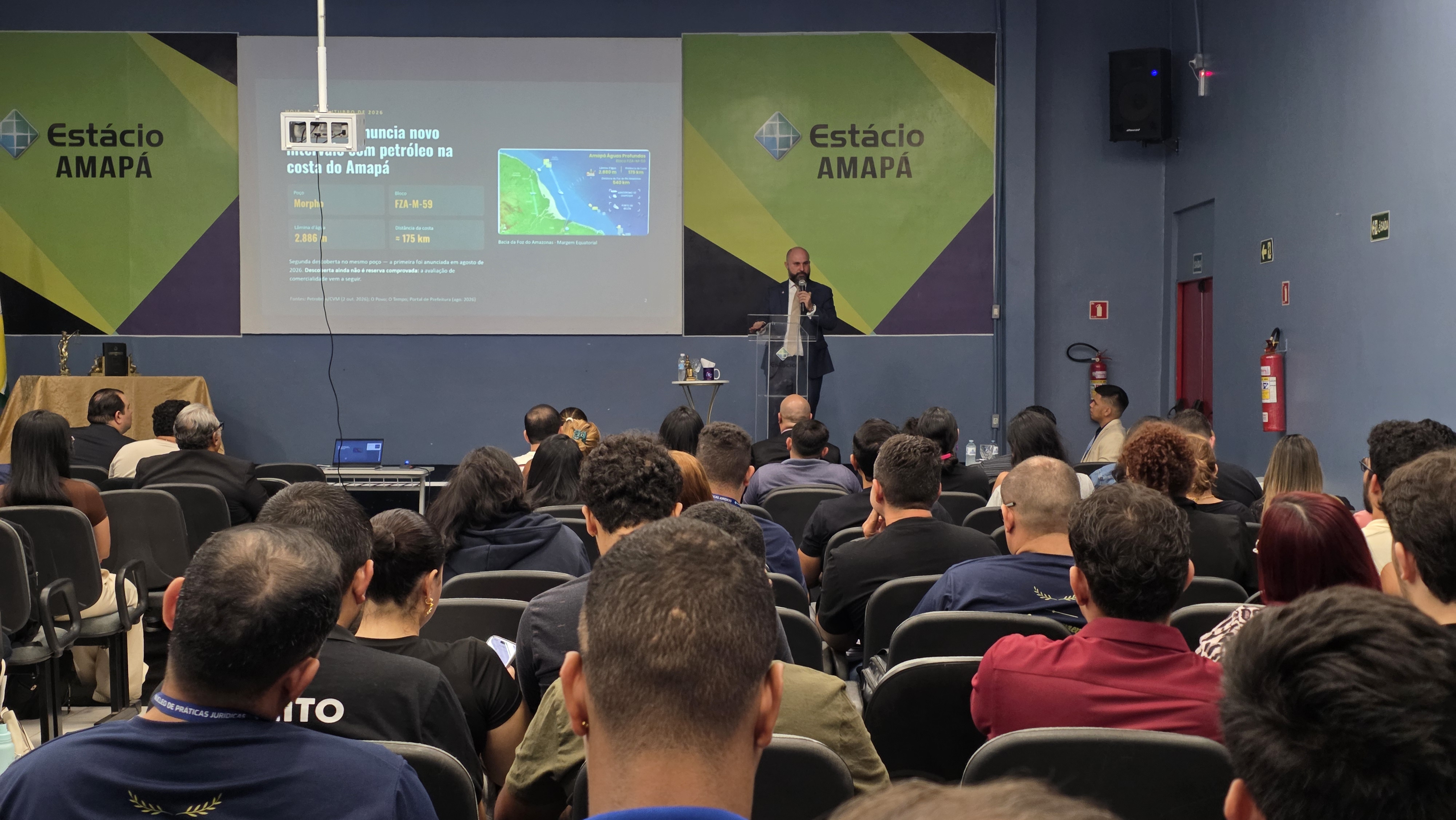 Registro da exposição no auditório da Estácio Amapá, com a discussão sobre petróleo na costa amapaense ao fundo.