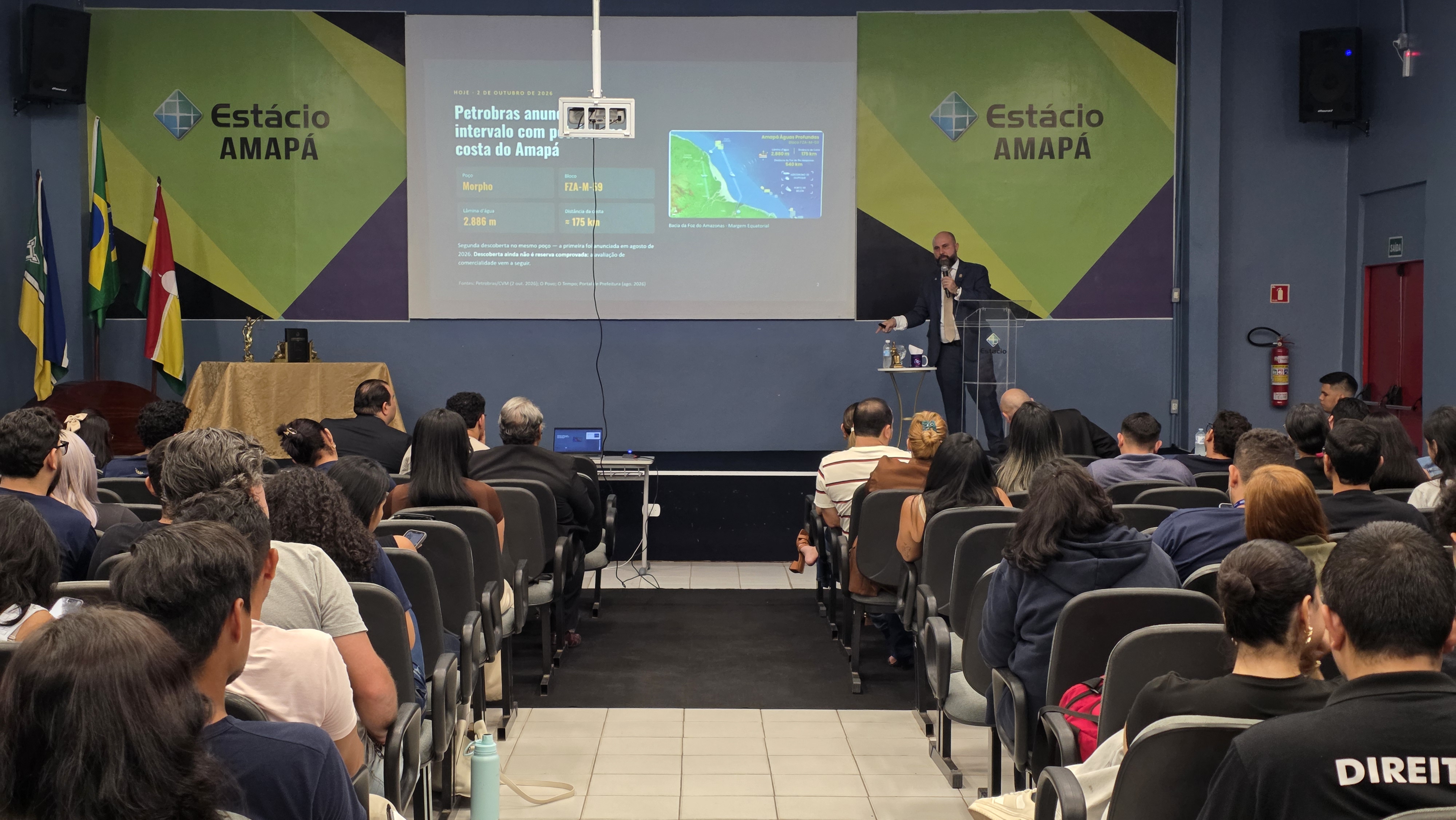 Palestra sobre a Margem Equatorial no auditório da Estácio Amapá, com o público acompanhando a apresentação projetada.